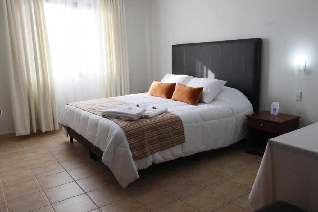 a bedroom with a large bed with two pillows on it at Hotel Qhawarina de Casas Kolping Bolivia S.R.L. in Sucre