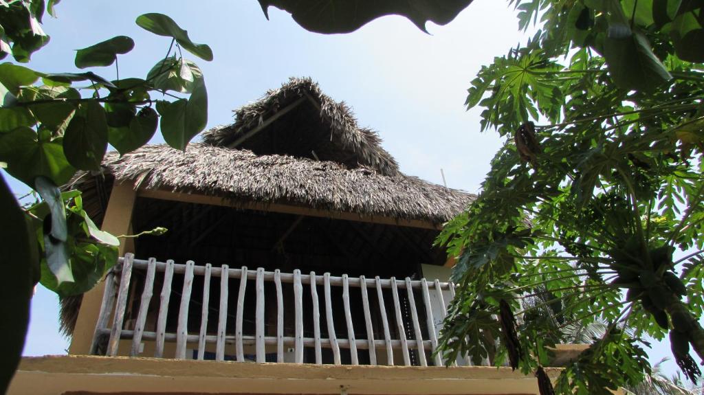un edificio con techo de paja y barandilla blanca en Hab #11 La Casa del Profe Salo, en Zapote