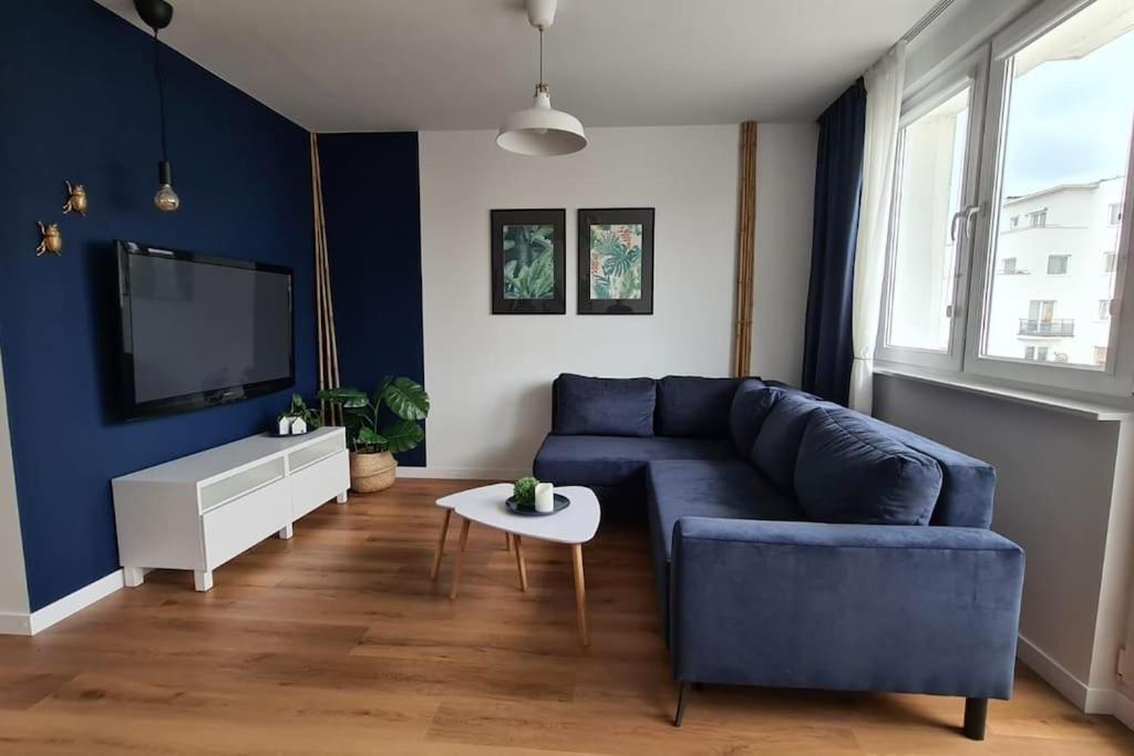 a living room with a blue couch and a tv at Słoneczny apartament w centrum Gdyni in Gdynia