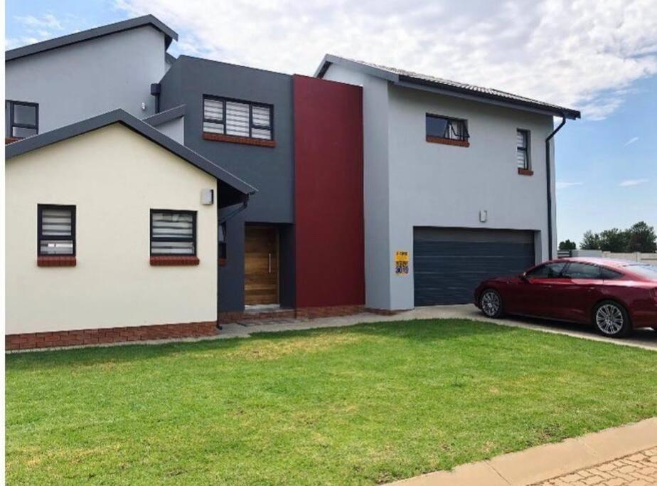 a red car parked in front of a house at Stunning gem by OR Tambo Airport in Benoni