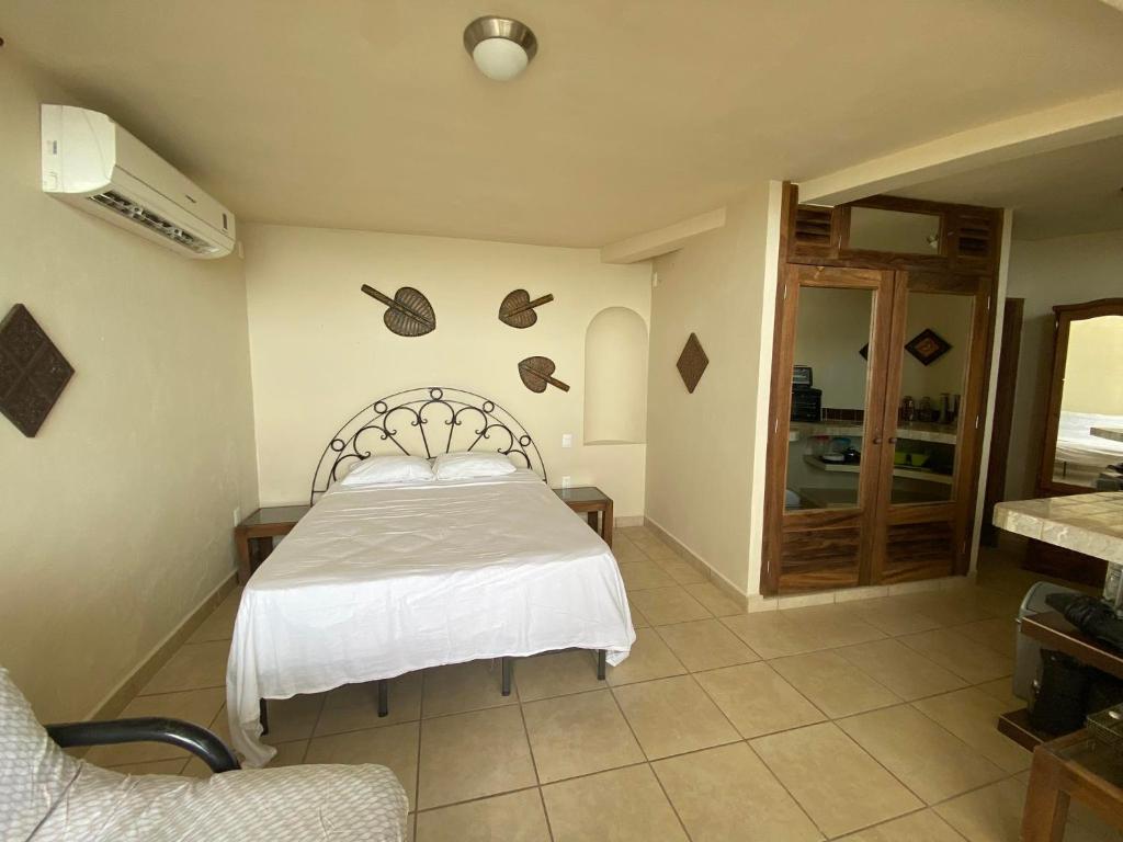 1 dormitorio con 1 cama con colcha blanca en Alojamientos Alexa en Sayulita