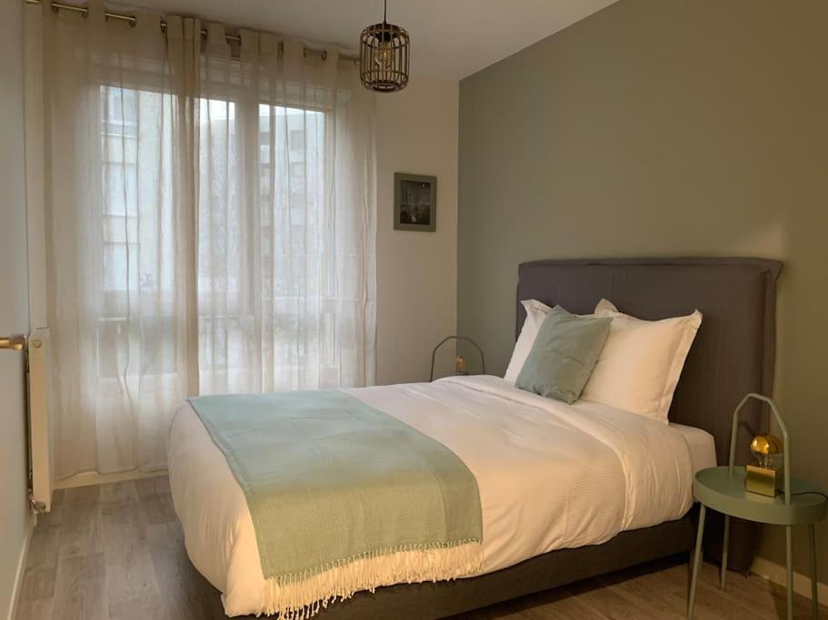 a bedroom with a large bed and a window at La demeure des Rois - Parking - Metro - Stade de France in Saint-Denis