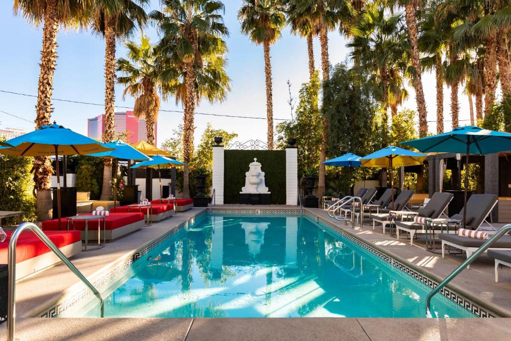 a pool with chairs and umbrellas and palm trees at The Lexi Las Vegas in Las Vegas