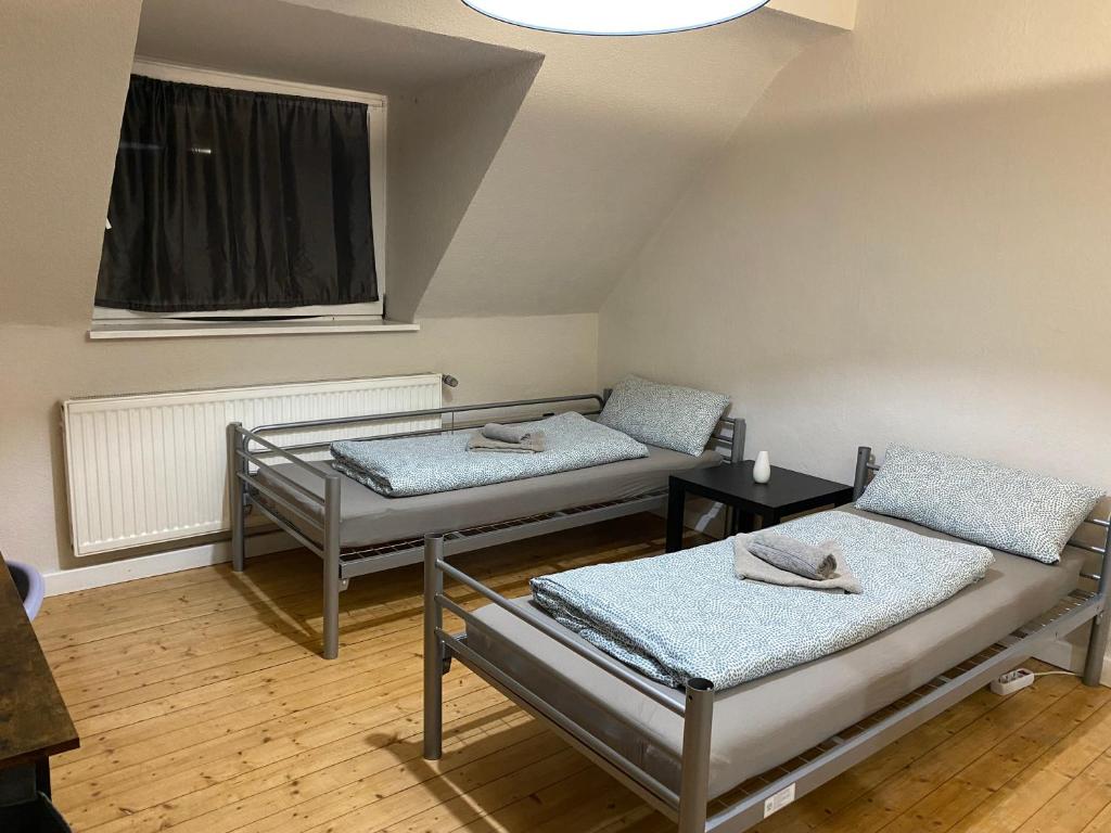 two beds in a small room with a window at Duisburg FeelHome, Flughafen nah,2-Schlafzimmer, Badewanne, Zentral, WiFi, Top Floor in Duisburg