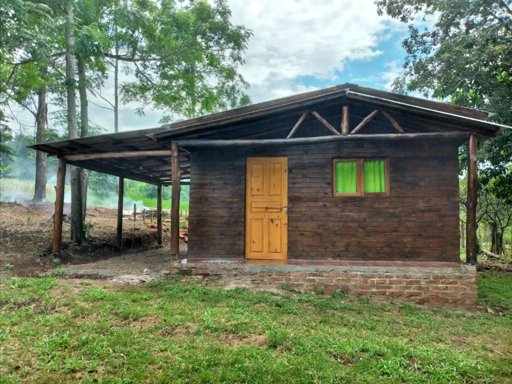 uma pequena casa de tijolos com uma porta e janelas verdes em Cabaña Guaimbe em Eldorado