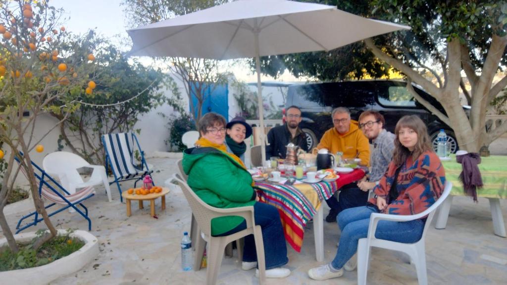 a group of people sitting at a table under an umbrella at Henchir ejdoud in Kairouan