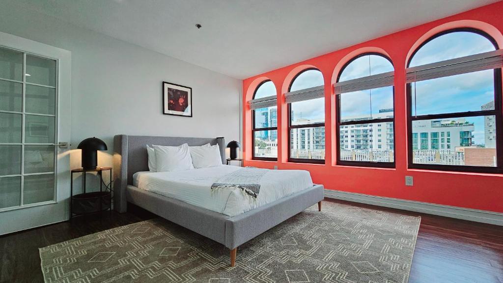 a bedroom with a bed with red walls and windows at The Lofts on Clematis 503 Downtown West Palm Beach in West Palm Beach