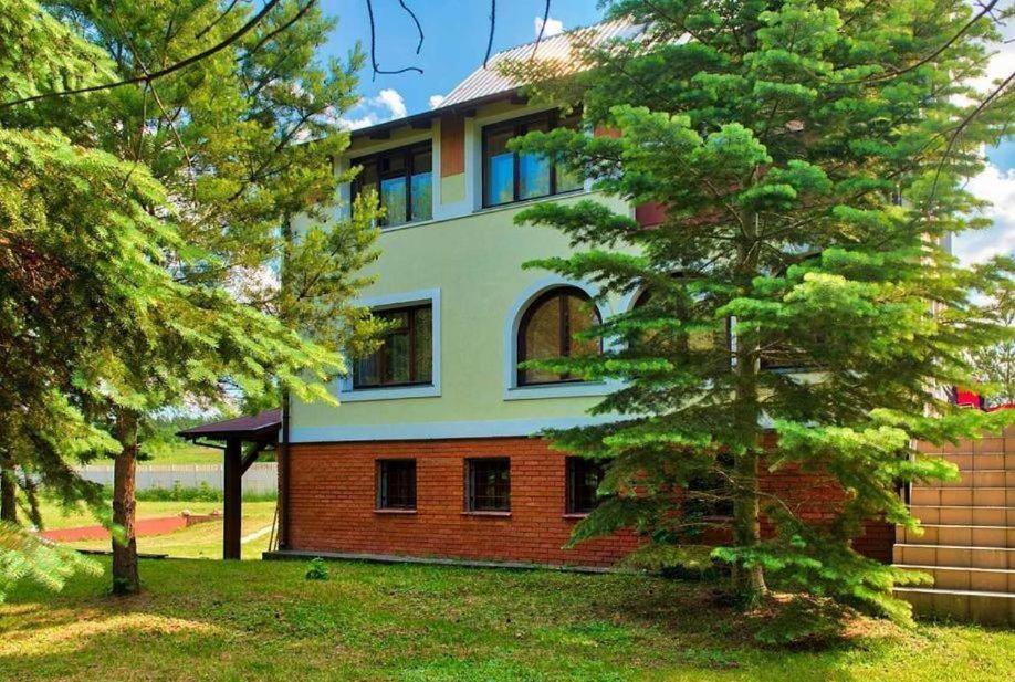 una casa con un árbol delante de ella en Pensjonacik Zacisze en Pasym