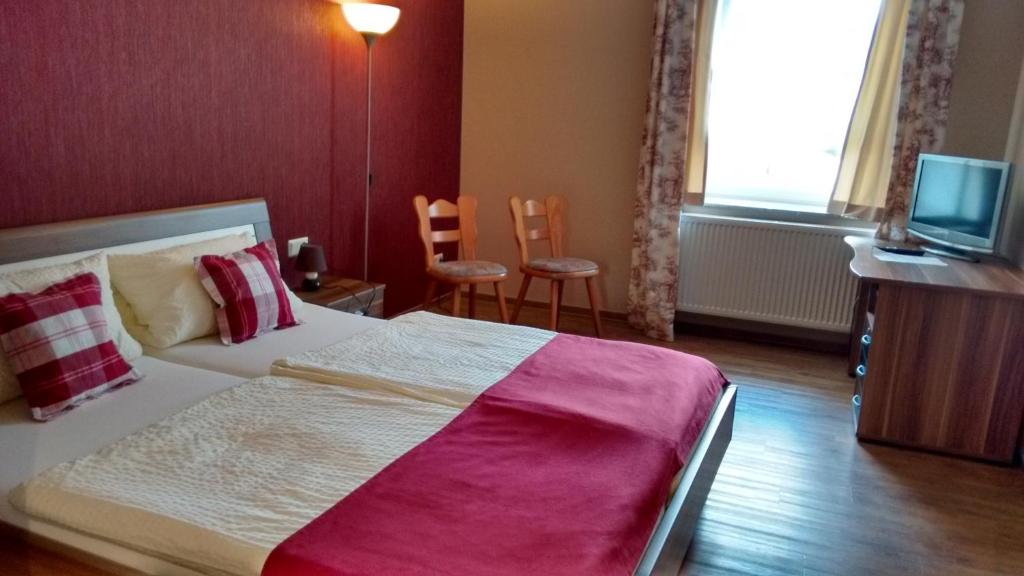 - une chambre avec un lit, deux chaises et une télévision dans l'établissement Landgasthaus Oberbillig, à Holsthum