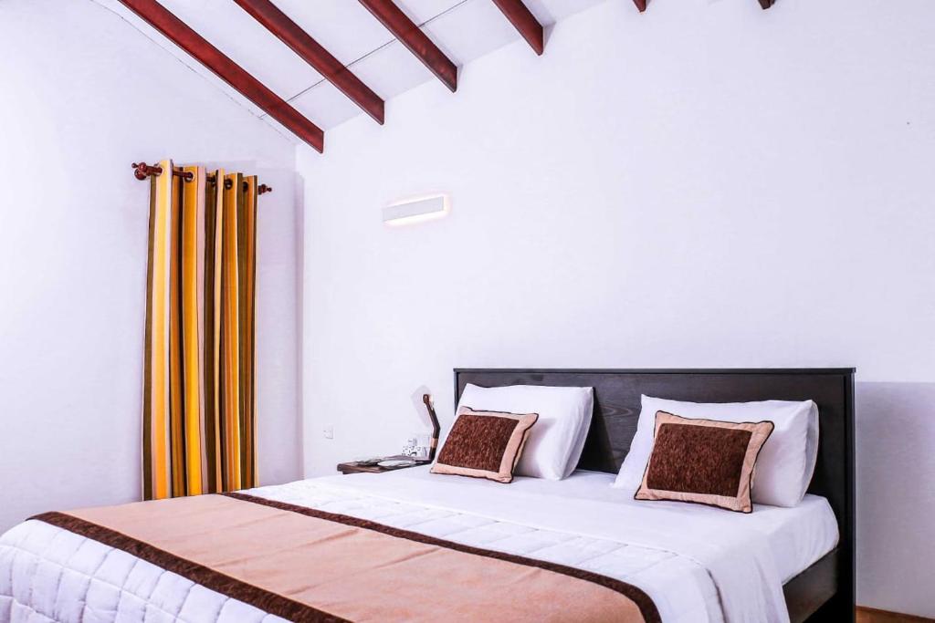 a bedroom with a large bed with yellow curtains at Quartz 2nd 14 Hotel in Kataragama