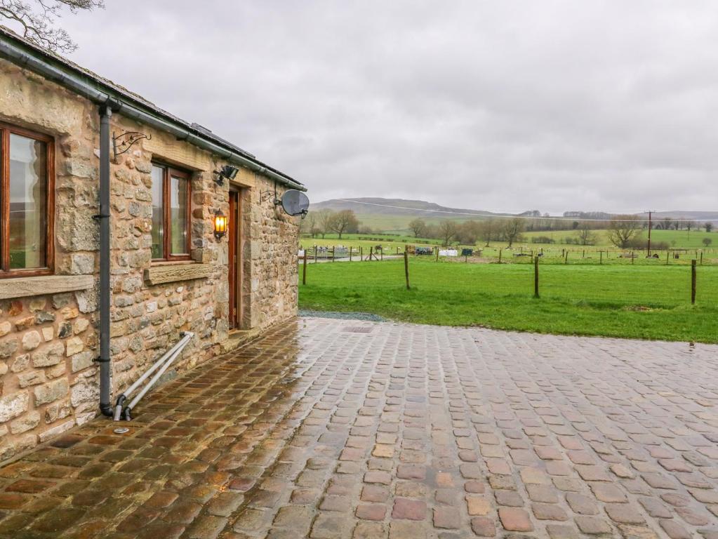 a stone building with a brick driveway next to a field at Orcaber Farm Retreat in Lancaster