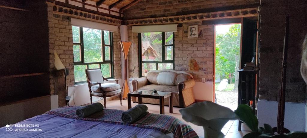 a bedroom with a bed and a chair and windows at Encanto - Habitación con baño privado in Villa de Leyva