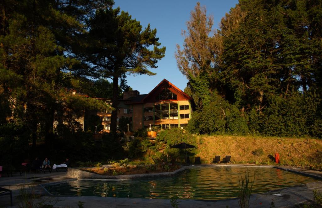 ein großes Haus mit einem Teich davor in der Unterkunft Hotel Puerta del Sur in Valdivia