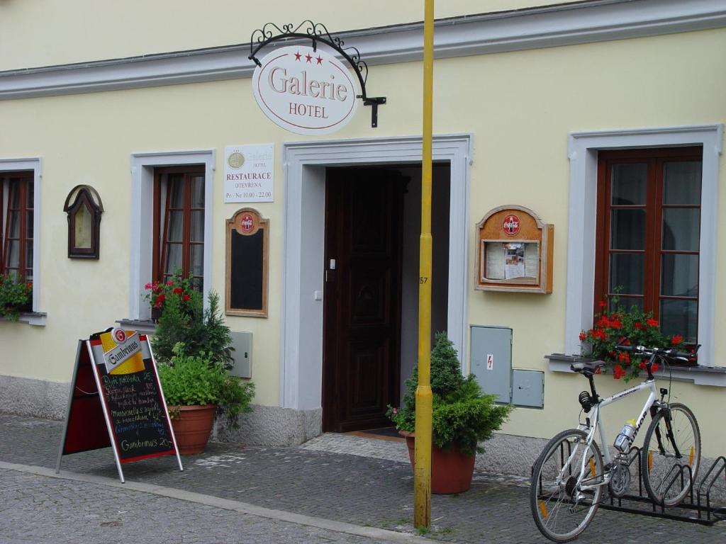 una bicicleta estacionada frente a un edificio con un cartel en Hotel Galerie en Třeboň