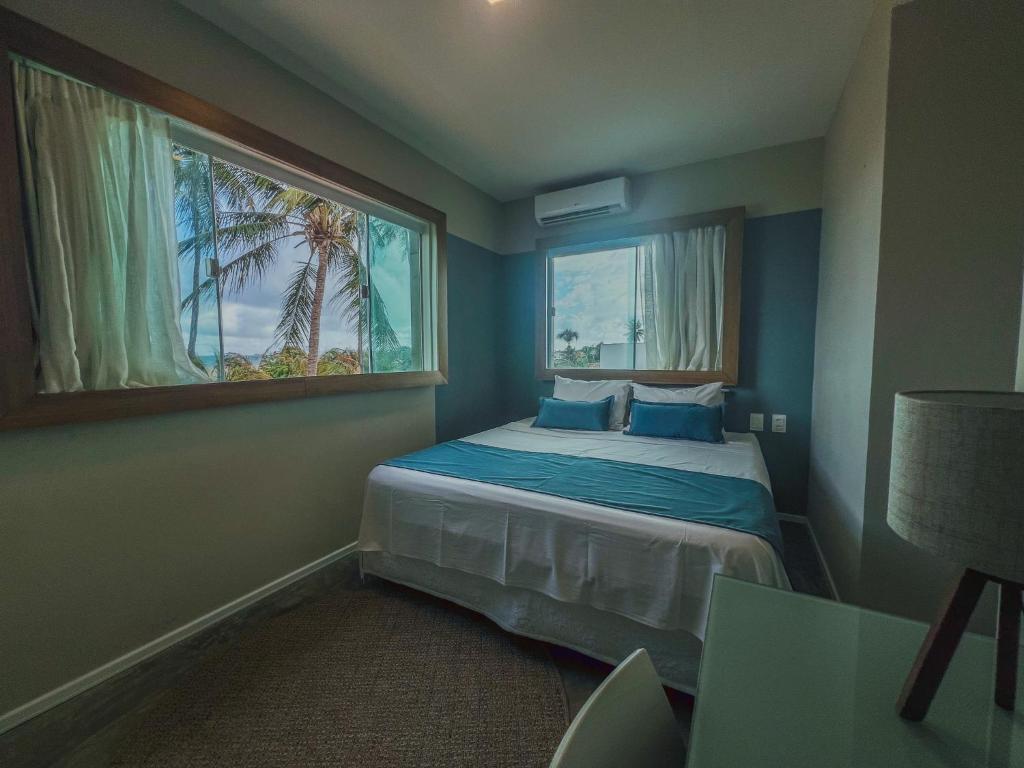 a bedroom with a bed and a window with a palm tree at Isla Beach Hotel in Pecém