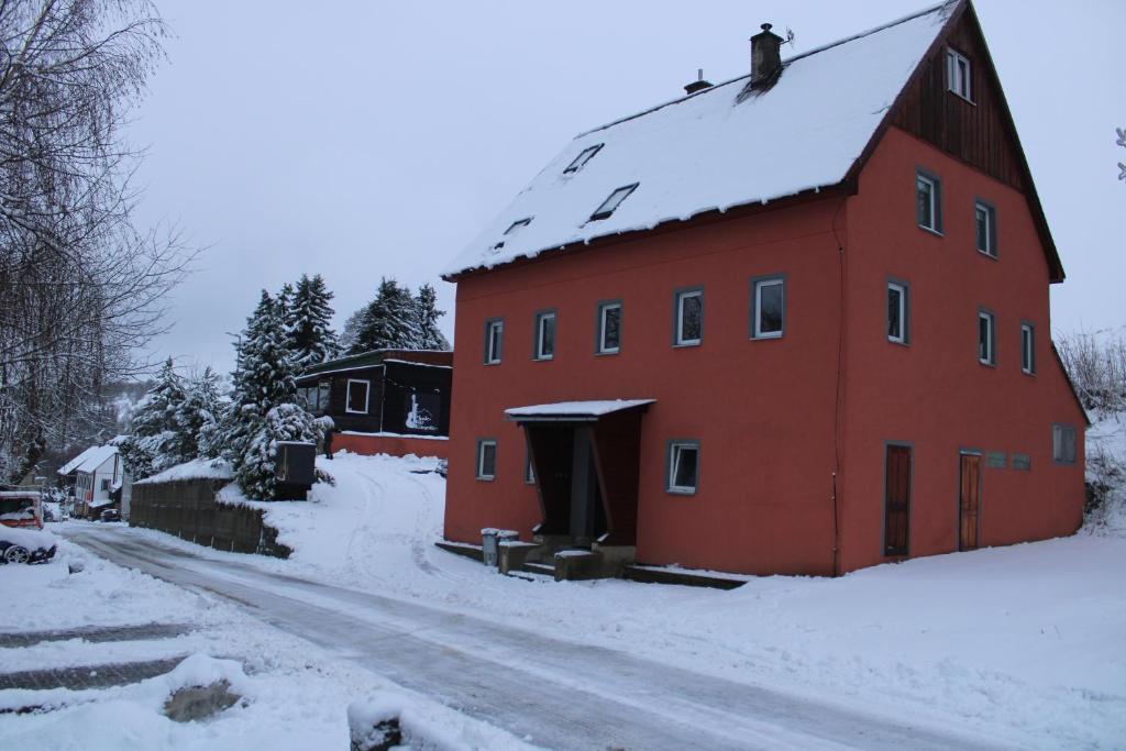 Czerwona stodoła ze śniegiem na dachu w obiekcie Apartmány Klínovec - Penzion Jonas w mieście Loučná pod Klínovcem