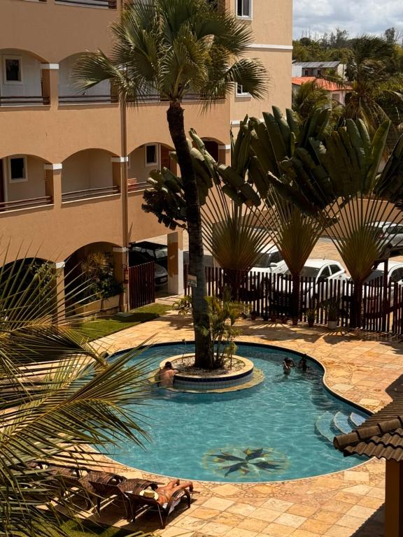 uma piscina com uma palmeira num edifício em Cumbuco Paradise Beach Apartment em Cumbuco