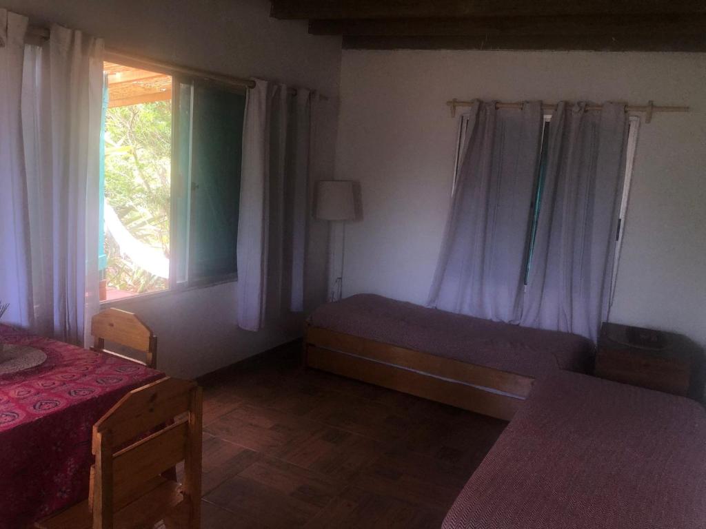 a bedroom with a bed and a window with curtains at La casita de Valizas in Barra de Valizas