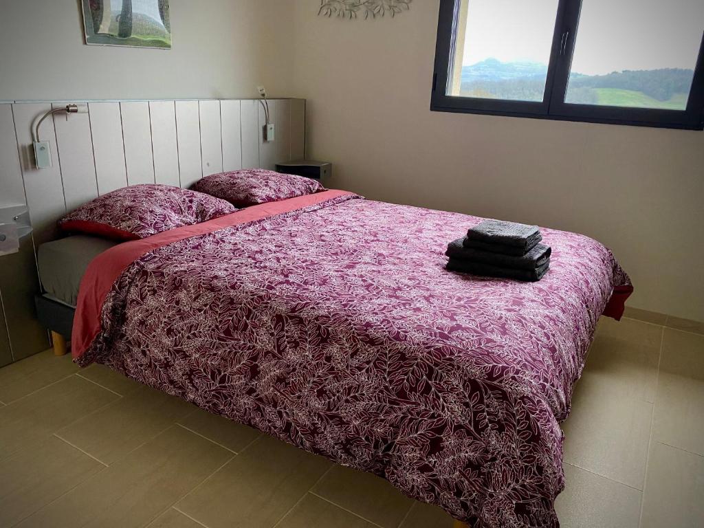 een slaapkamer met een bed met een roze dekbed bij L’écrin des bois in Mansac