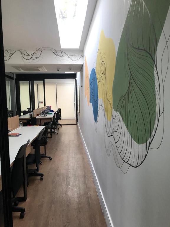 Coworking Coletivo Zen في ساو باولو: مكتب به مكاتب وطاولات وجدران جدارية