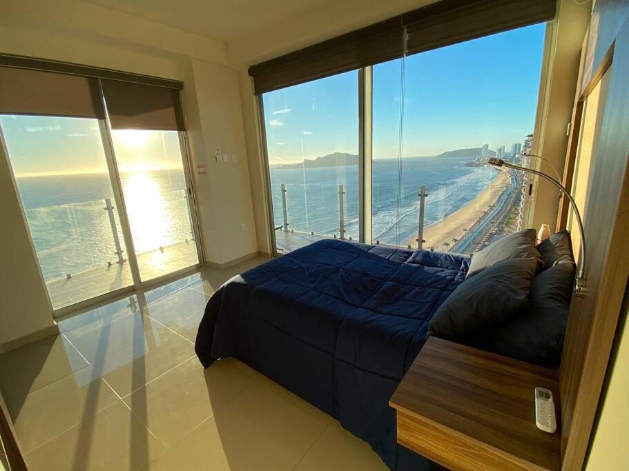 a bedroom with a bed and a large window at Departamento con vista al mar in Mazatlán