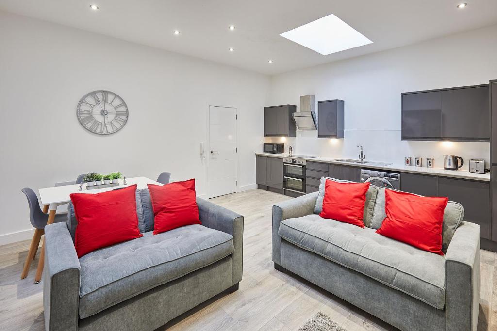 una sala de estar con 2 sofás con almohadas rojas en The Hideaway - Apartment 8 en Sunderland