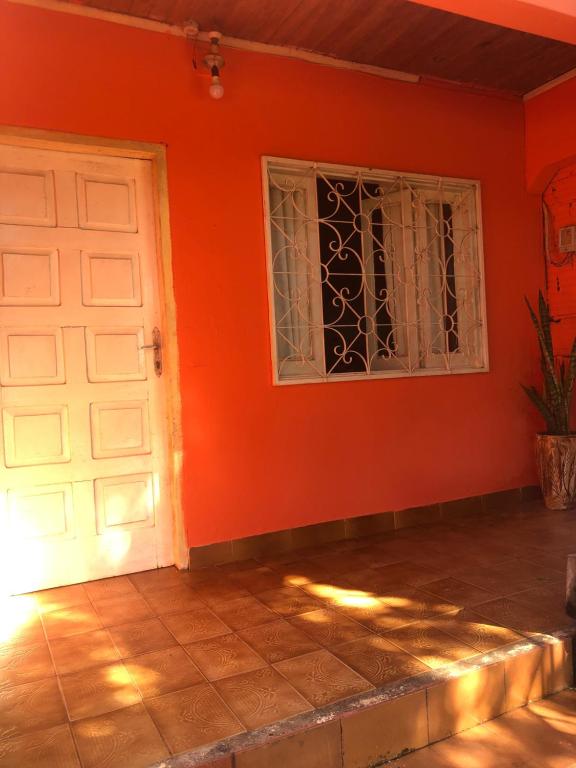 Habitación naranja con puerta blanca y ventana en HOSPEDAJE PRÓCERES DE MAYO, en Encarnación