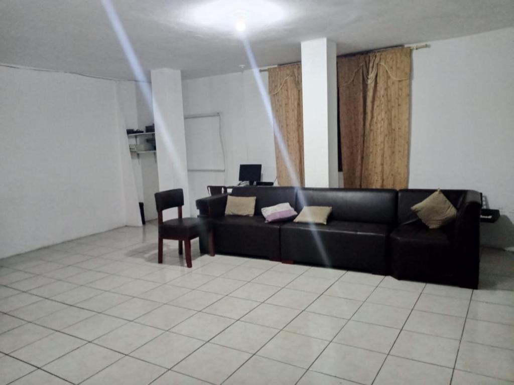 sala de estar con sofá negro y silla en FLAVIO REZABALA, en Manta