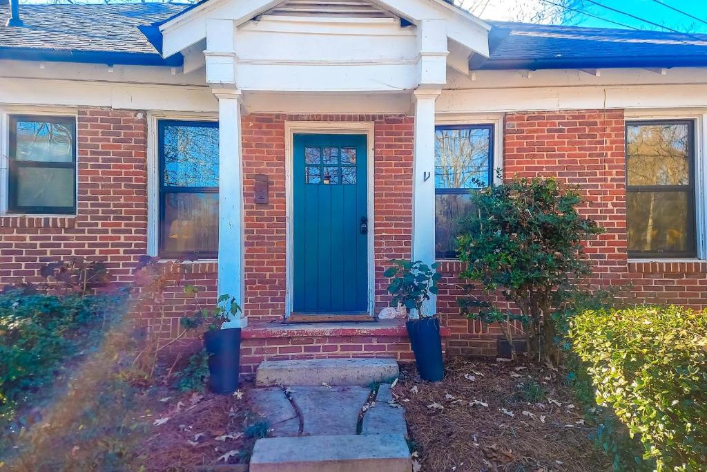uma casa de tijolos com uma porta azul e duas plantas em Brickstone Bohemian, Unit B em Decatur