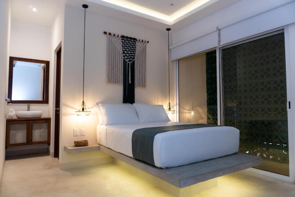 a bedroom with a large white bed and a bathroom at Kanté Hotel - Downtown Tulum in Tulum