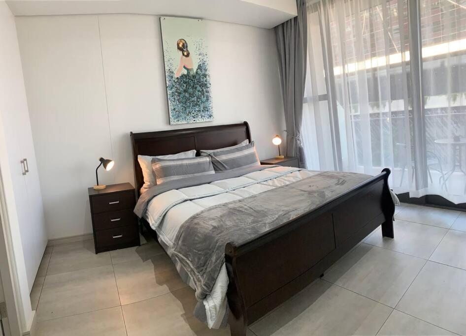 een slaapkamer met een groot bed en een raam bij Modern Exec 2Bed Apartment at Infinite in Johannesburg