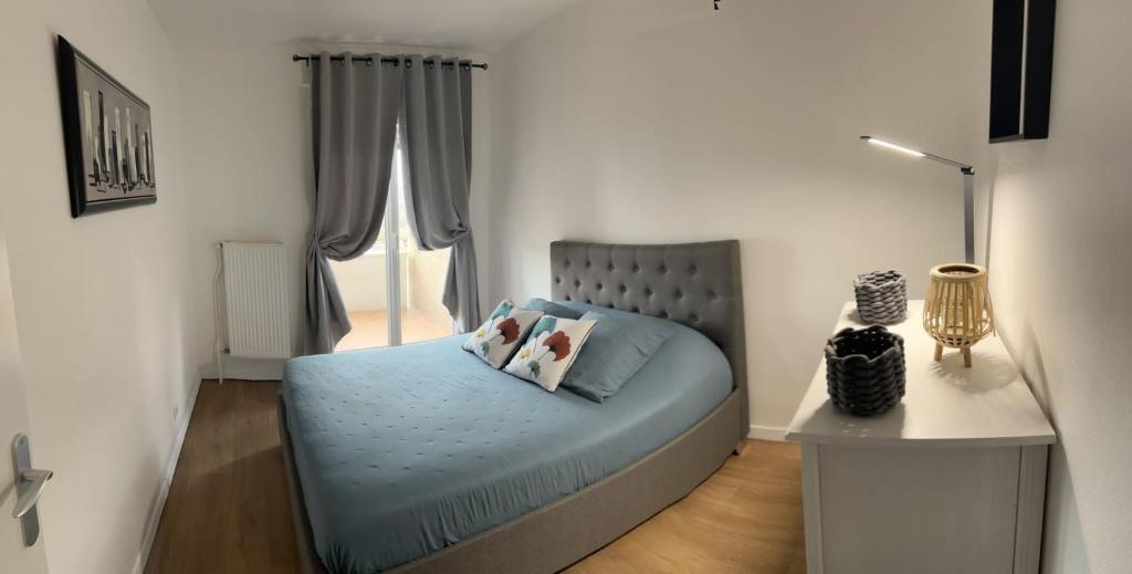 une chambre avec un lit avec des draps bleus et une fenêtre dans l'établissement ASMAR, à Toulouse