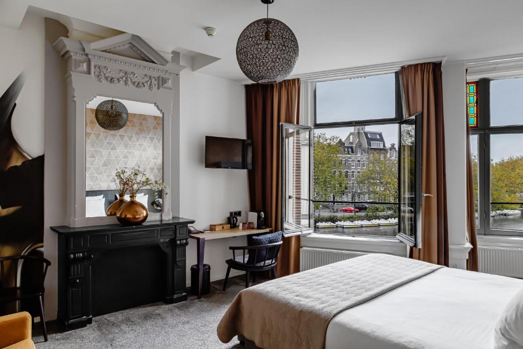 een slaapkamer met een bed, een bureau en ramen bij Boutique Hotel View in Amsterdam