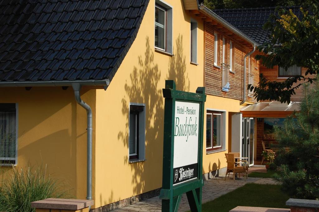 una casa amarilla con un cartel delante en Pension Buchfink, en Ückeritz