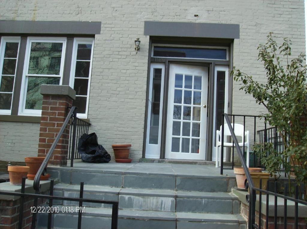 um gato preto sentado no alpendre da frente de uma casa em Pleasant Rooming House em Washington