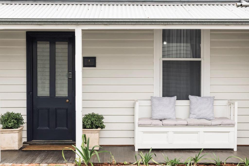 eine Veranda mit einer weißen Bank und einer schwarzen Tür in der Unterkunft Benambra Cottage c1860 - PET FRIENDLY in Queenscliff