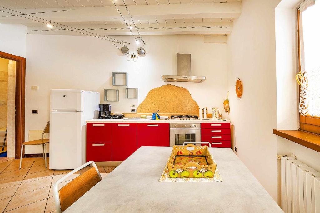uma cozinha com armários vermelhos e um frigorífico branco em La Piazzetta centralissimo ristrutturato Wifi em Caprino Veronese