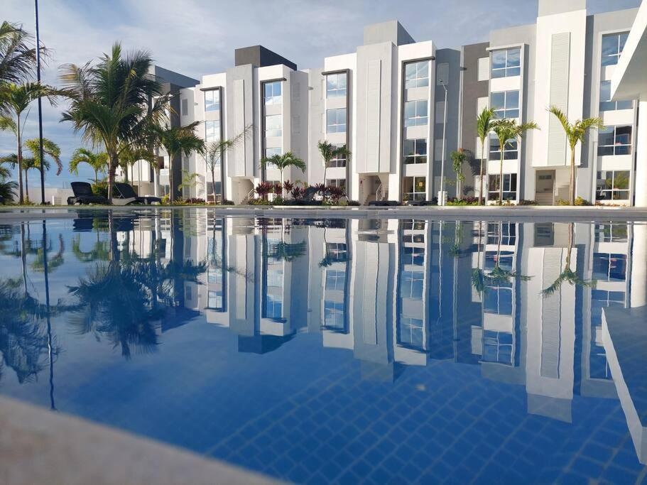 a hotel with a swimming pool in front of a building at Bonito departamento planta baja en zona diamante in Barra Vieja
