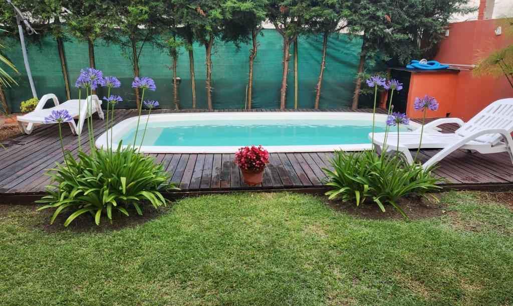 a swimming pool with two chairs and flowers in a yard at Casa en Santa Teresita in Santa Teresita