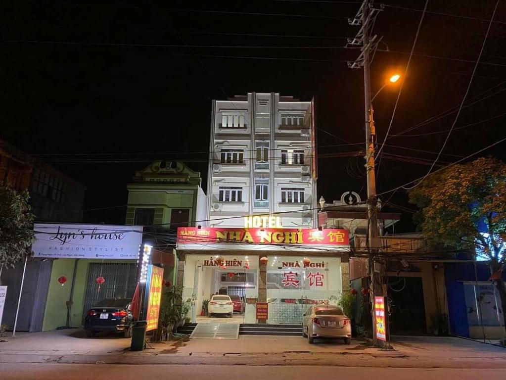 Lục Ngạn的住宿－hằng hiên hotel，前面有 ⁇ 虹灯标志的白色建筑