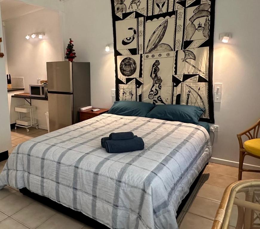 a bedroom with a bed with a blue and white blanket at Magnetic Island Resort Studio in Nelly Bay