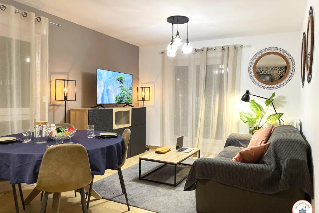 - un salon avec une table, des chaises et une télévision dans l'établissement Le Port Enchanté - Parking - Terrasse, à Caen