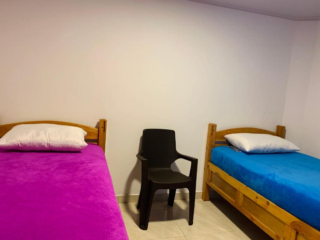 a room with two beds and a chair in it at Hostel Bogotá Kings in Bogotá