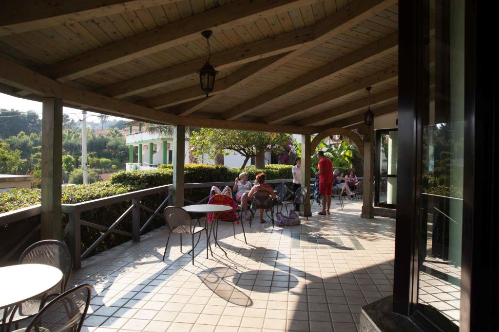 a patio with tables and chairs and people sitting at Hotel MARINELLA parking wi-fi spiaggia attrezzata in Capo Vaticano