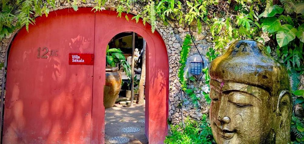 uma porta vermelha com uma estátua em frente em Exquisite private Villa — Villa Sekala, Sanur, SE Bali em Sanur