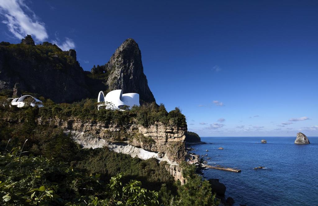 a building on a cliff next to the ocean at Healing Stay KOSMOS in Ullŭng