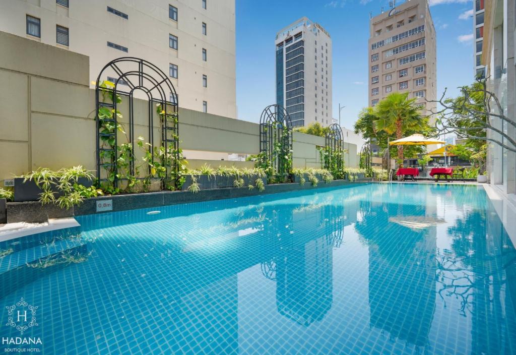 a swimming pool in a building with tall buildings at Hadana Boutique Hotel Danang in Da Nang