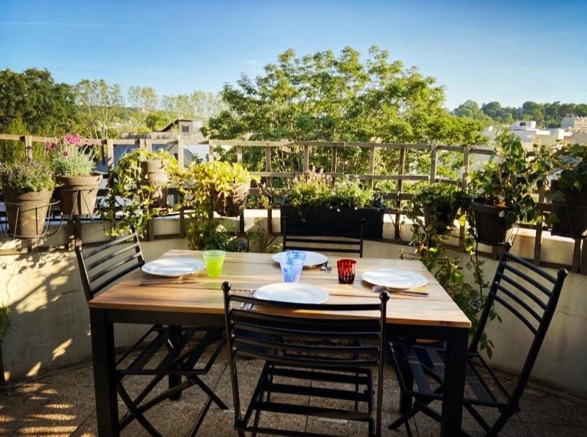 a wooden table with four chairs on a patio at L'Eden Urbain - Issy-les-Moulineaux in Issy-les-Moulineaux