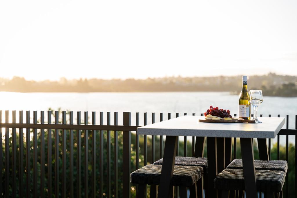 una mesa con una botella de vino y dos sillas en Harbour Haven - A Sunset Oasis! en Tauranga