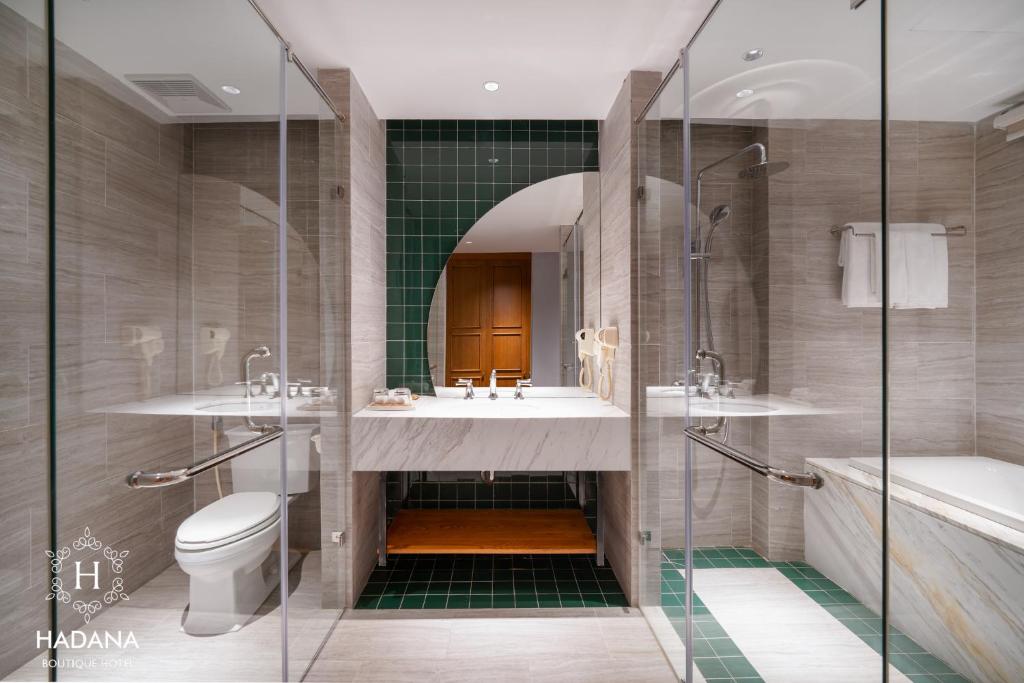 A marble-finished bathroom with a separate glass shower, bathtub, toilet and double vanity.